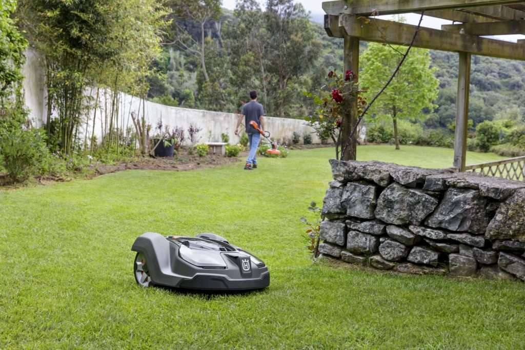 Automower 315x robotic lawn mower near stone wall